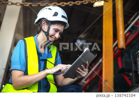 Woman in hard hat and high-visibility vest uses tablet Woman in hard hat and high-visibility vest uses tablet 138742104