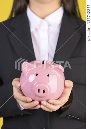 豚の貯金箱を持つスーツを着た女性 138742258