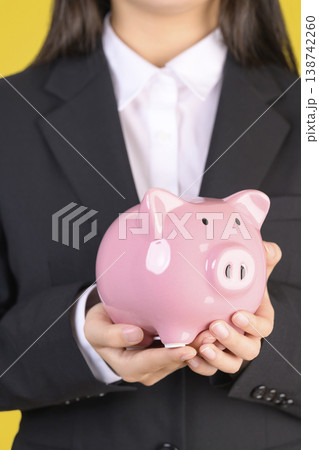 豚の貯金箱を持つスーツを着た女性 138742260