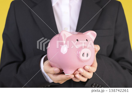 豚の貯金箱を持つスーツを着た女性 138742261