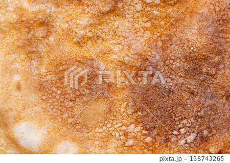 Golden thin pancake with surface texture. Stacked softedged pancake with airy bubbles. Finetextured pancake with translucent appearance and airy bubbles on simple white dish 138743265