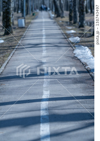City route with snow shadows. Mountain bike trail featuring snowy streets and sunlight patterns. City street cycling lane decorated with snow and play of sunlight shadows 138743497