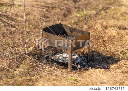 Silent scene of abandoned barbecue outdoors. Deserted grill resting silently in sundried grasslands. Abandoned barbecue stand left untouched amidst arid and sunbaked plains Silent scene of abandoned barbecue outdoors. Deserted grill resting silently in sundried grasslands. Abandoned barbecue stand left untouched amidst arid and sunbaked plains 138743715