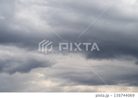 Heavy gray clouds gather above horizon. Overcast sky with threatening storm clouds looming overhead. Foreboding storm clouds cast dark and dramatic atmosphere across sky Heavy gray clouds gather above horizon. Overcast sky with threatening storm clouds looming overhead. Foreboding storm clouds cast dark and dramatic atmosphere across sky 138744069