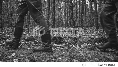 Low angle view of two Wehrmacht soldiers walking in boots through forest 138744608