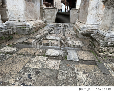 Ancient Roman road with stone pavement leading to steps in historic architectural setting Ancient Roman road with stone pavement leading to steps in historic architectural setting 138745546
