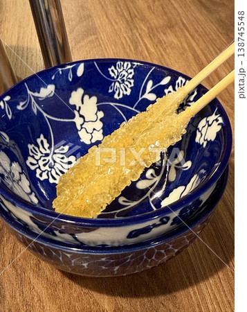 Rock sugar stick on floral blue ceramic bowl sitting on wooden table Rock sugar stick on floral blue ceramic bowl sitting on wooden table 138745548