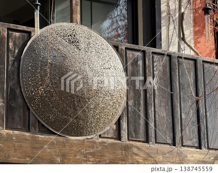 Ornate shield mounted on rustic wooden wall with warm lighting from hanging lamps 138745559
