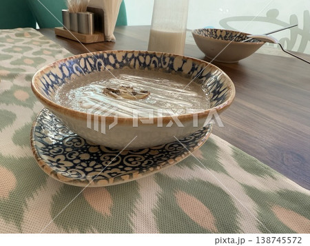 Bowl with decorative patterns filled with latte on cafe table offers rustic dining background 138745572