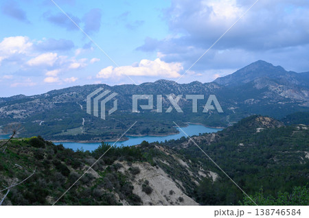 Majestic mountain landscape with serene lake nestled among rolling hills during a tranquil afternoon 138746584