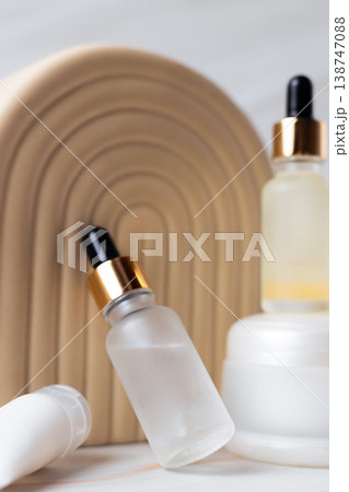 Skincare cosmetic products with serum dropper bottles and cream containers on minimal beige podium, beauty skincare routine concept 138747088
