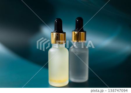 Frosted glass cosmetic dropper bottle on natural stone with dark blue background, skincare serum packaging mockup, minimal beauty product concept 138747094