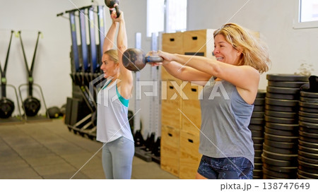 Women training with kettlebells performing strength exercises in gym 138747649