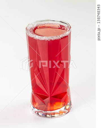 Vibrant red berry drink in a faceted glass tumbler, isolated on a clean white background. 138748343