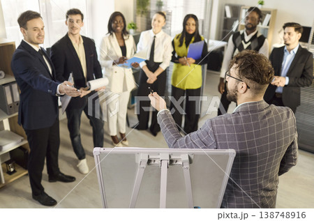 Business team in office workshop with male presenter engaging colleagues standing 138748916