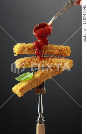 Fish fingers with basil and ketchup on a fork. Fish fingers with basil and ketchup on a fork. 138749440