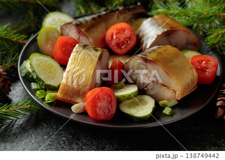 Smoked mackerel with fresh cucumbers, tomatoes and green onions on a black plate. 138749442