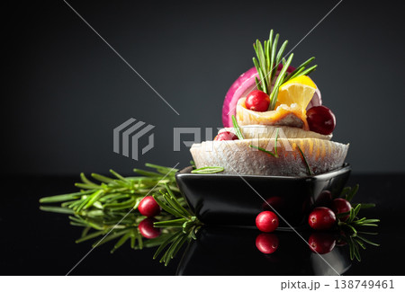 Herring fillet in oil with lemon, onion, rosemary, and cranberries. 138749461