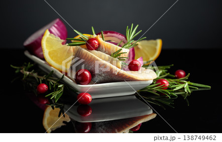 White dish with herring on a black reflective background. 138749462