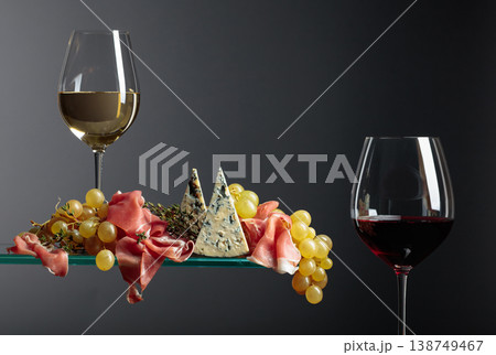 Glasses of red and white wine with snacks. Grapes with blue cheese, prosciutto and thyme. 138749467