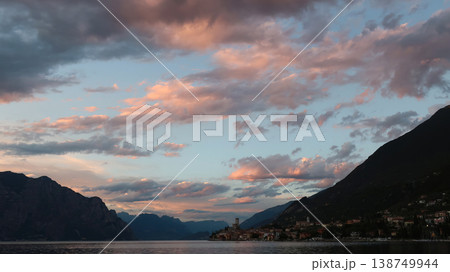 Evening sky with pink clouds above calm lake and rocky shores Evening sky with pink clouds above calm lake and rocky shores 138749944