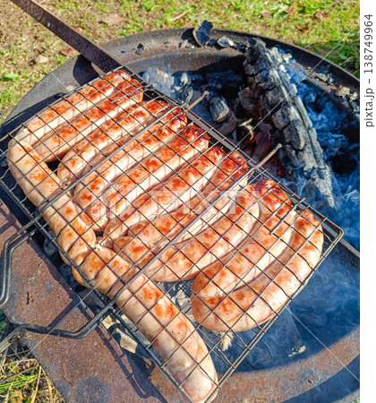 Sausages grill on a wire rack beside smoldering charcoal Sausages grill on a wire rack beside smoldering charcoal 138749964
