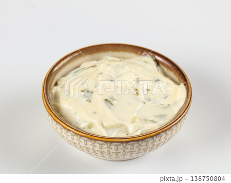 Creamy tartar sauce with herbs and pickles in a patterned ceramic bowl isolated on white 138750804