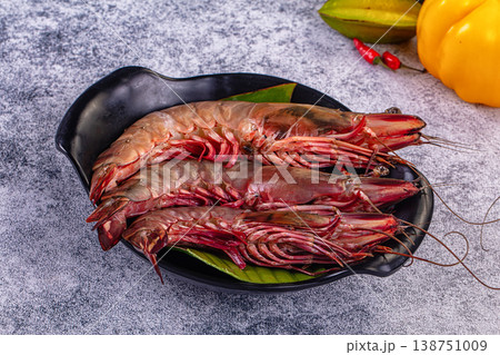 Fresh raw giant red prawns on a plate with chili peppers and tropical vegetables. 138751009