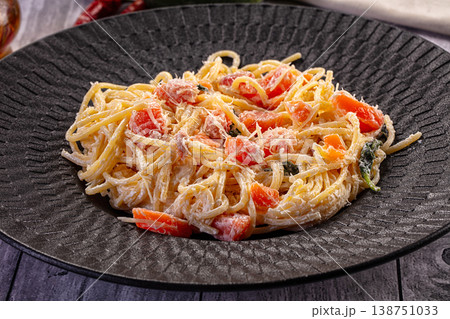 Gourmet pasta with salmon and creamy parmesan sauce on a rustic wooden table. 138751033