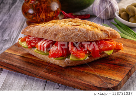Gourmet smoked salmon and avocado ciabatta sandwich on a rustic wooden board. Gourmet smoked salmon and avocado ciabatta sandwich on a rustic wooden board. 138751037