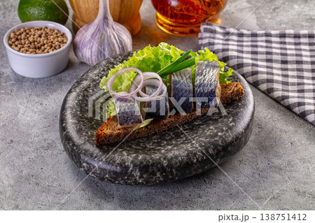 Rustic open-faced sandwich with salted herring, onion, and lettuce on dark rye bread 138751412