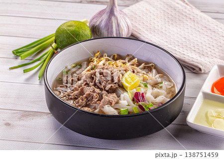 Vietnamese pho bo soup with beef, rice noodles and fresh herbs on a white wooden table Vietnamese pho bo soup with beef, rice noodles and fresh herbs on a white wooden table 138751459