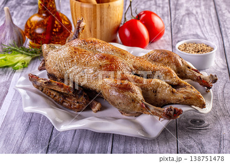 Gourmet roasted ducks with crispy skin served on a platter with fresh tomatoes and herbs 138751478