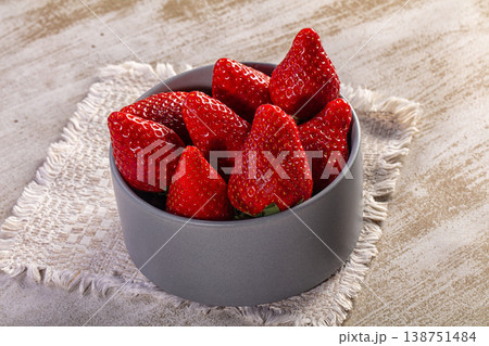 Fresh ripe red strawberries in a grey ceramic bowl on a rustic wooden table with a woven placemat Fresh ripe red strawberries in a grey ceramic bowl on a rustic wooden table with a woven placemat 138751484