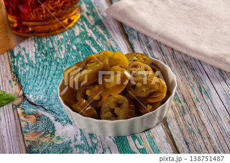 Sliced pickled jalapeno peppers in a white bowl on a rustic wooden table 138751487