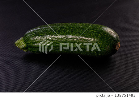 Single fresh green zucchini vegetable isolated on a dark black background Single fresh green zucchini vegetable isolated on a dark black background 138751493