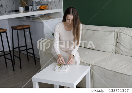 Beautiful woman opening jewelry box and sitting on sofa in modern interior at home 138751597