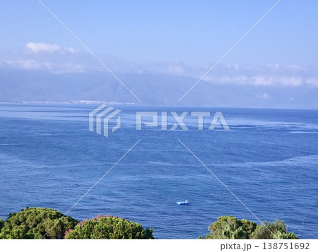 Picturesque view to blue sea and mountain island on horizon in mist. Calm water surface, background for traveling and vacation,Beautiful sea view, sailboats far away in the sea in sunny day. Picturesque view to blue sea and mountain island on horizon in mist. Calm water surface, background for traveling and vacation,Beautiful sea view, sailboats far away in the sea in sunny day. 138751692