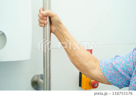 Asian elderly woman patient use toilet support rail in bathroom. Asian elderly woman patient use toilet support rail in bathroom. 138753176