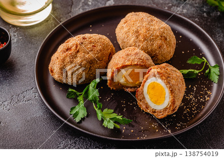 Traditional Scotch Eggs on a black plate. 138754019