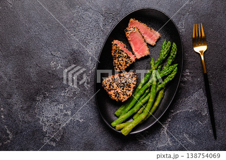 Tuna steak fried in sesame seeds served with asparagus. 138754069