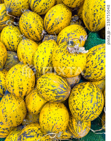 Yellow striped melons piled together in a vibrant display, showcasing their unique patterns and textures in a market setting Yellow striped melons piled together in a vibrant display, showcasing their unique patterns and textures in a market setting 138755048
