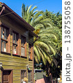 Traditional wooden house exterior with large palm trees and clear blue sky in a sunny residential area 138755058