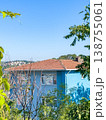 Blue residential building with red tiled roof surrounded by trees and clear blue sky in a suburban neighborhood 138755061