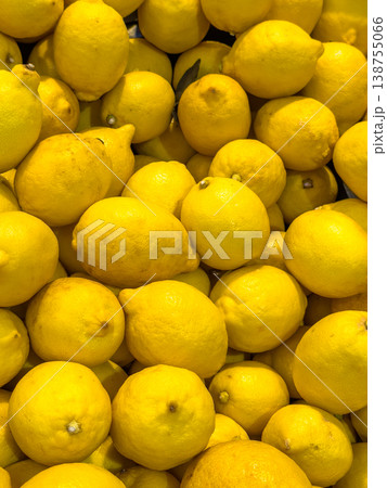 Fresh yellow lemons piled together in a vibrant display, showcasing their smooth skin and natural shine in a market setting Fresh yellow lemons piled together in a vibrant display, showcasing their smooth skin and natural shine in a market setting 138755066