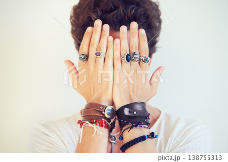 Hands, face and cover with a man in studio on a white background for fashion or style accessories. Jewelry, bracelet and rings on the fingers of a young model closeup for trendy or edgy expression Hands, face and cover with a man in studio on a white background for fashion or style accessories. Jewelry, bracelet and rings on the fingers of a young model closeup for trendy or edgy expression 138755313