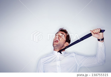 Stress, mental health and a man choking on his tie in studio on a white background with mockup space. Depression, anxiety and strangle for self harm with an unhappy young person shouting in anger Stress, mental health and a man choking on his tie in studio on a white background with mockup space. Depression, anxiety and strangle for self harm with an unhappy young person shouting in anger 138755315