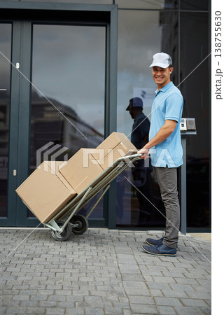 Box, portrait or trolley with a happy delivery guy by office for entrance for online shopping or product. Apartment, hand truck or courier man with stock by a home for ecommerce service or package Box, portrait or trolley with a happy delivery guy by office for entrance for online shopping or product. Apartment, hand truck or courier man with stock by a home for ecommerce service or package 138755630