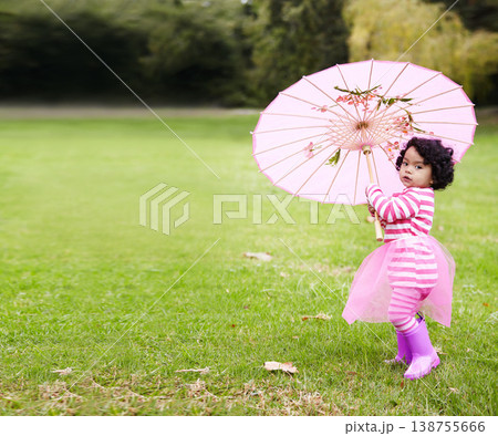 Umbrella, walking and girl child in a garden walking on the grass on summer weekend. Adorable, playful and young kid, baby or toddler with curly hair playing on the lawn in outdoor field or park. 138755666