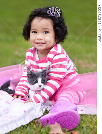 Nature, crown and girl with kitten in a garden on grass on a summer weekend together. Happy, sunshine and portrait of child with tiara sitting and having fun with cat, animal or pet on lawn in field. 138756057